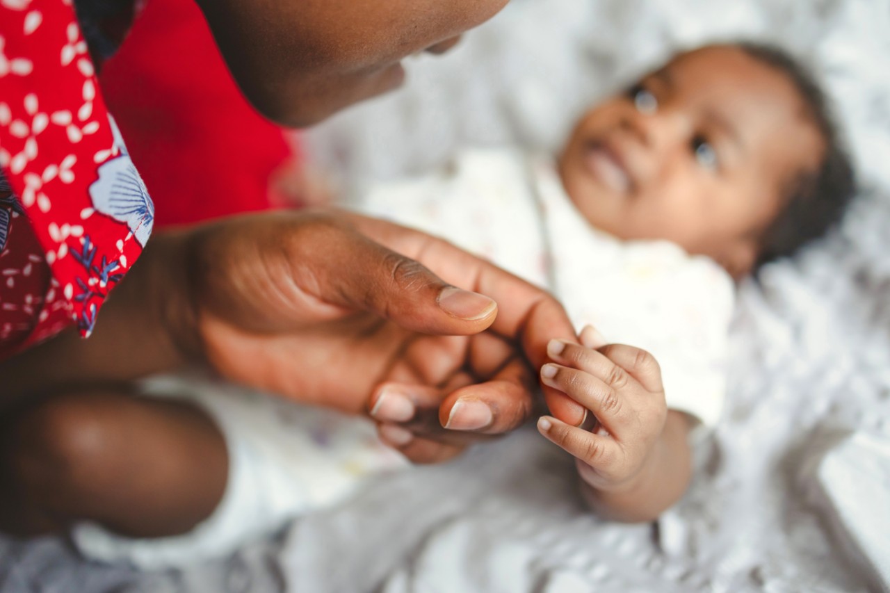 A parent holds baby's hand