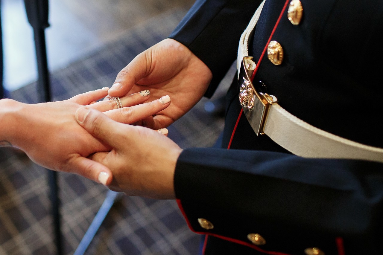 A person in military uniform places a ring on another person's hand
